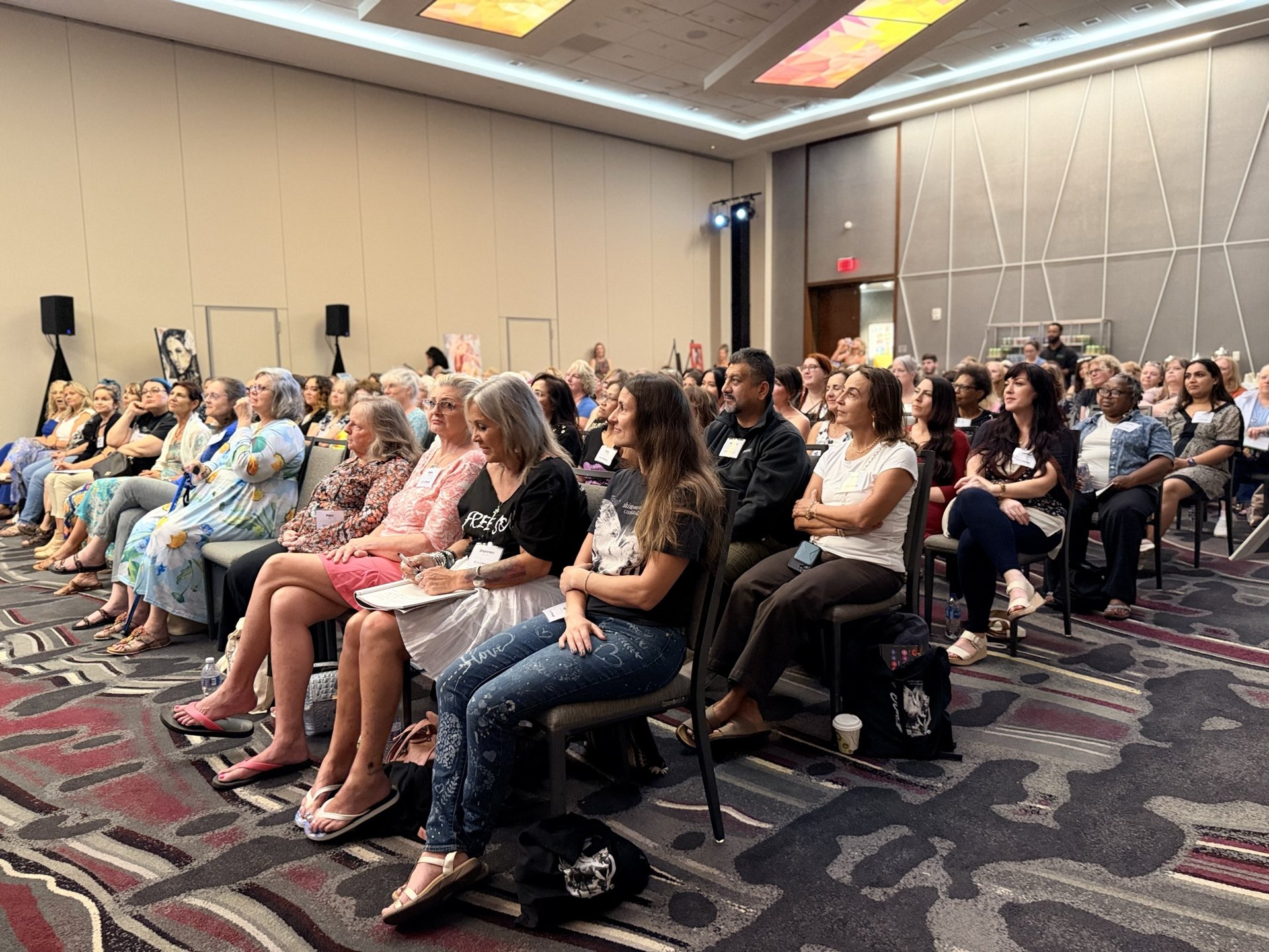The packed ballroom at Milan Art Experience 2026 on Thursday night, rows of artists in name badges turned toward the stage, the front row laughing.
